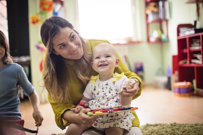 Mother and baby in a playgroup smiling and playing on a xylophone