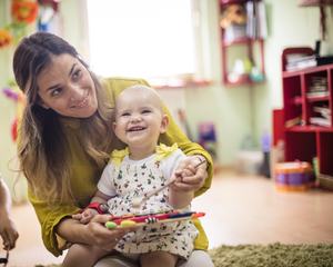 Mother and baby in a playgroup smiling and playing on a xylophone