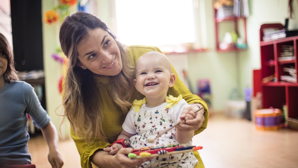 Mother and baby in a playgroup smiling and playing on a xylophone