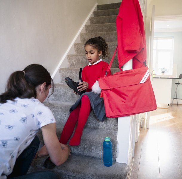 Mother helping her daughter put on school shoes