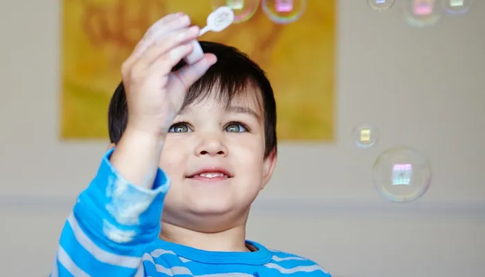 Mother looking at young and happy son blowing bubbles
