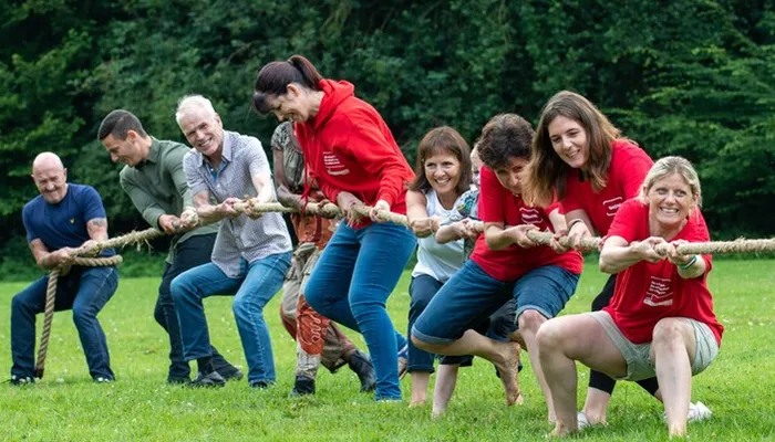 Foster families and Action for Children staff playing tug of war at an event