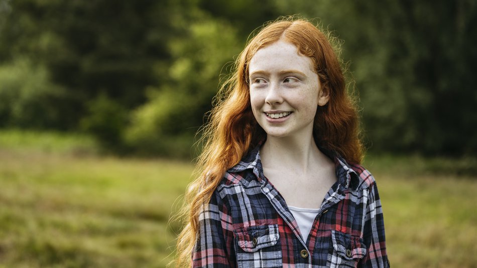 Outdoor portrait of smiling adolescent girl in woodland area