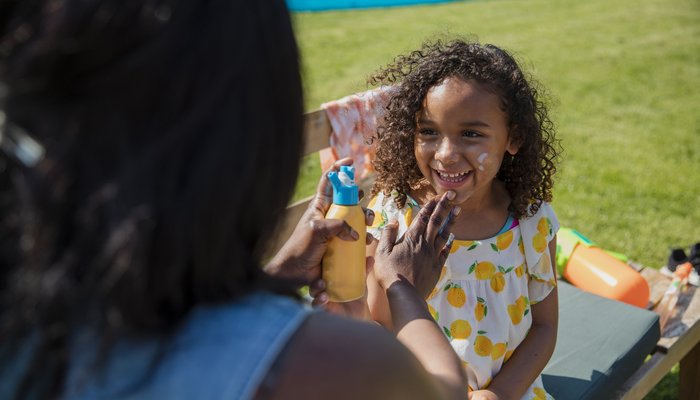 Over the shoulder view of a mother putting suncream on her daughter