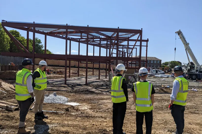 Three young people in high-vis visiting a construction site