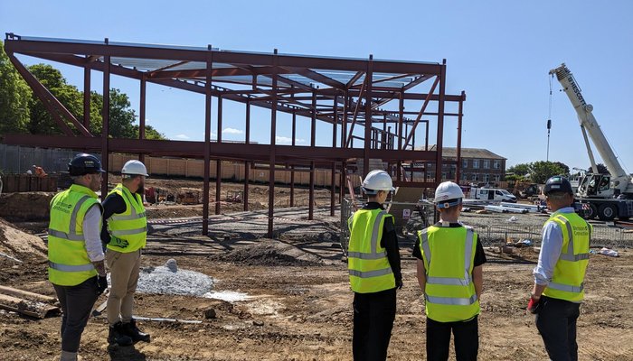 Three young people in high-vis visiting a construction site