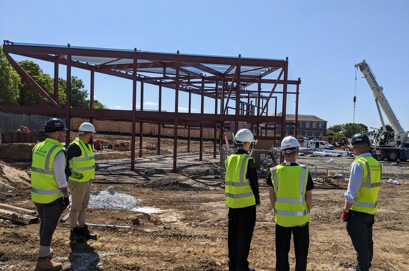 Three young people in high-vis visiting a construction site