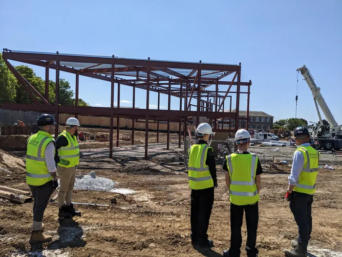 Three young people in high-vis visiting a construction site