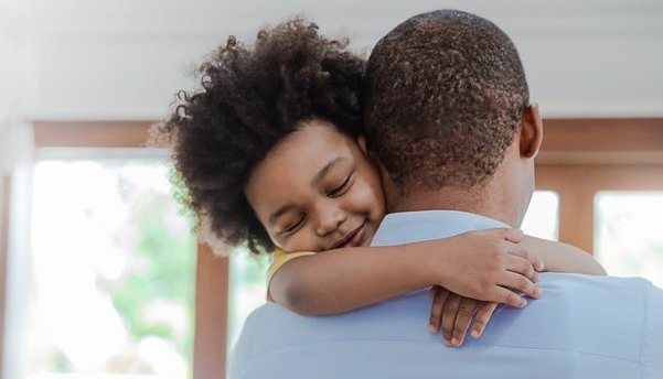 Father and son hugging in living room and smiling