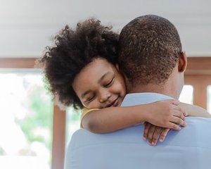 Father and son hugging in living room and smiling