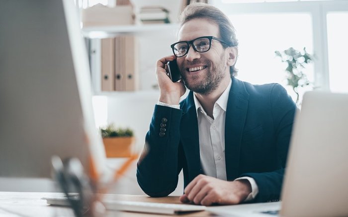 Professional man sitting at his desk talking on mobile phone