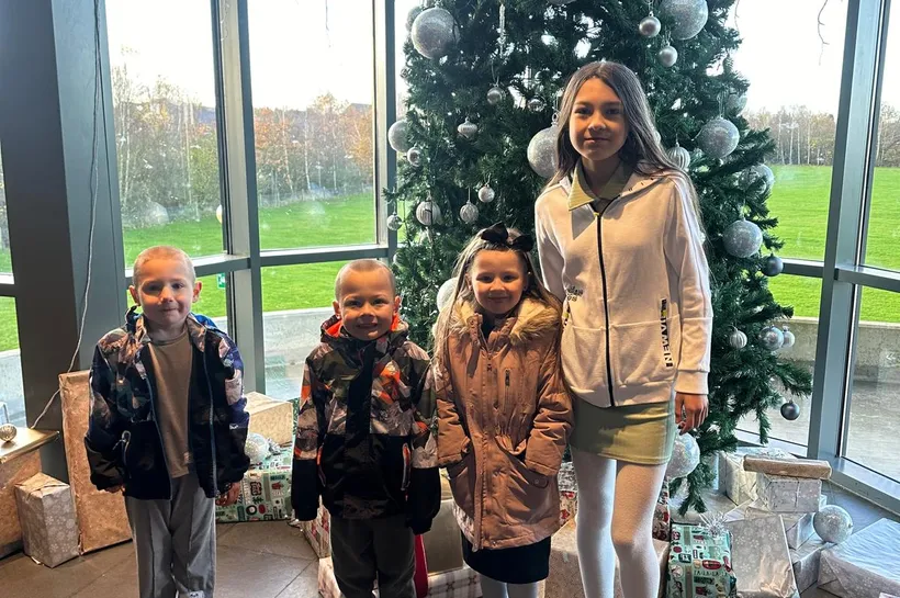 Happy children standing in front of Christmas tree