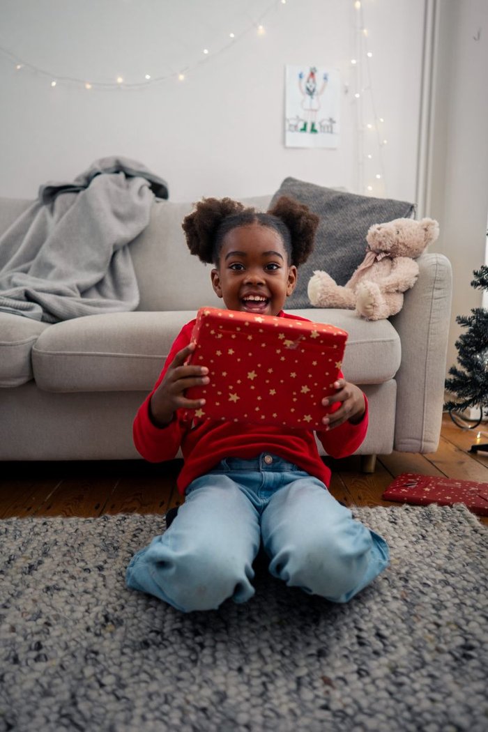 A young child holding a present and smiling at the camera