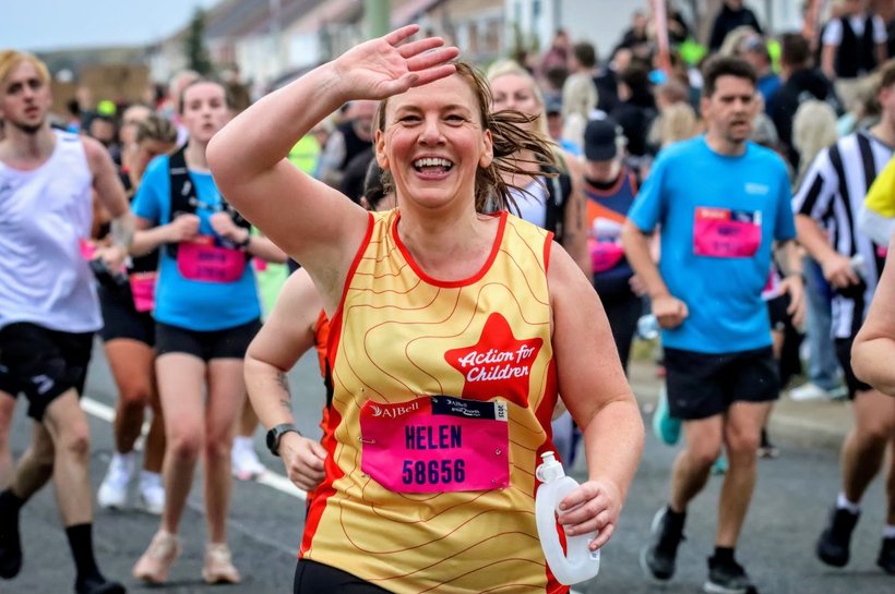 An Action for Children runner, running a half marathon and waving at the camera