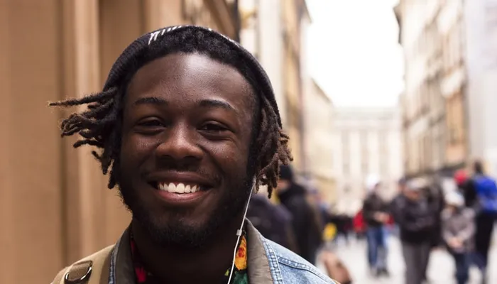 Teenage boy wearing headphones walking down crowded city street