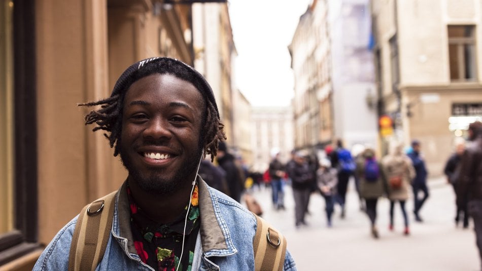 Teenage boy wearing headphones walking down crowded city street