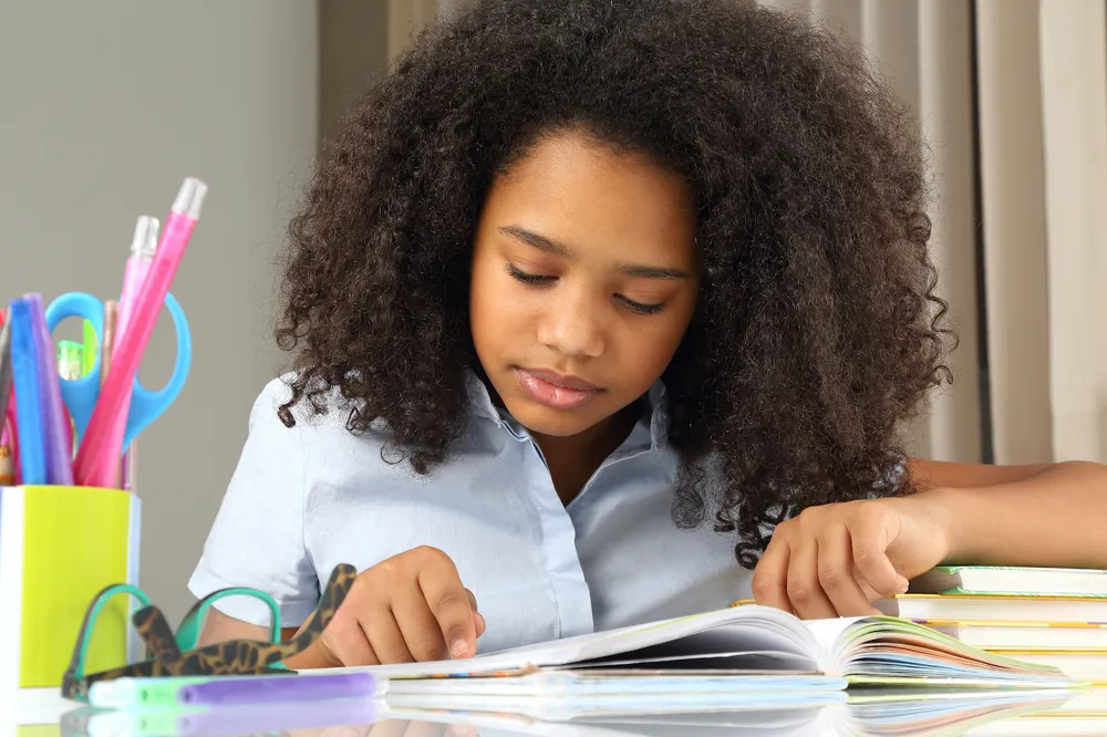 Teenage girl sitting at desk studying school books