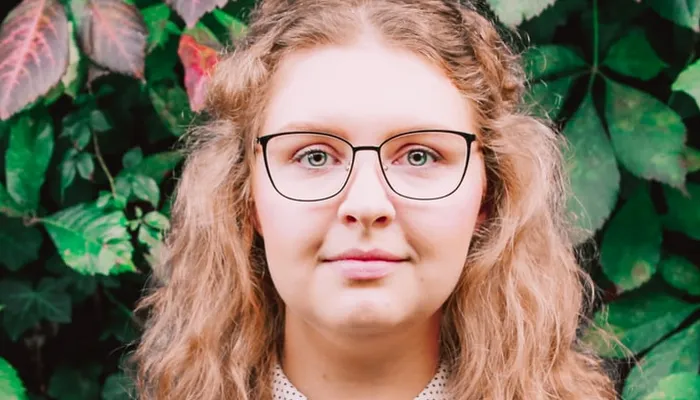 Teenage girl wearing glasses standing in front of plants