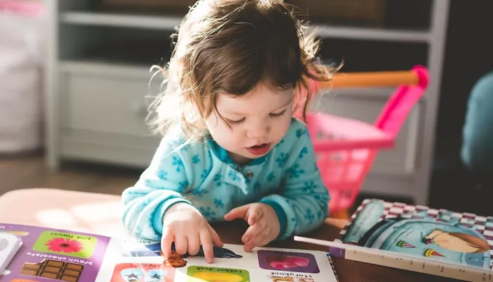 Toddler sat at coffee table reading childrens books