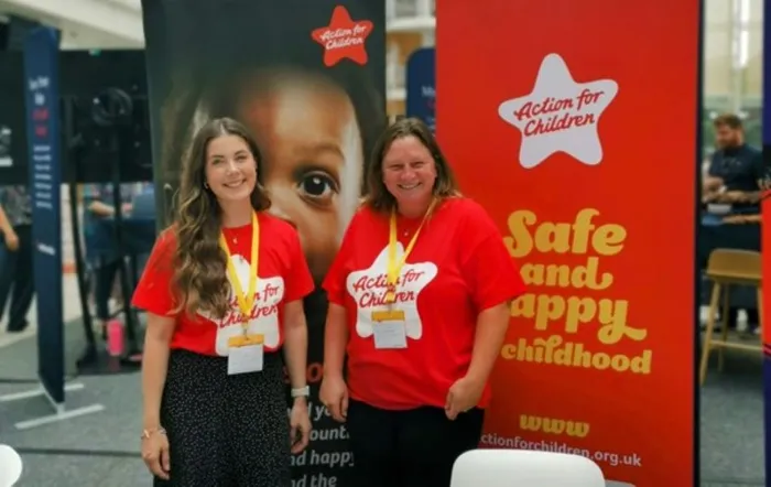 Two Action for Children workers standing in front of two large Action for Children banners