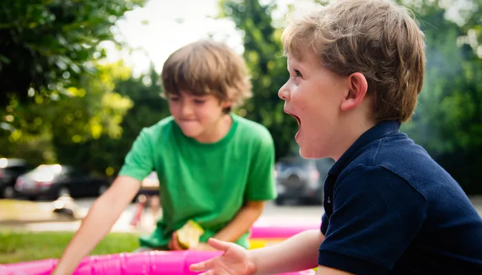 Two boys splashing water in paddling pool