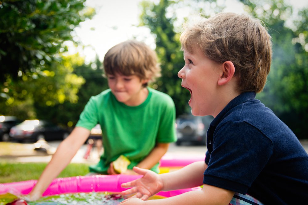 Two boys splashing water in paddling pool