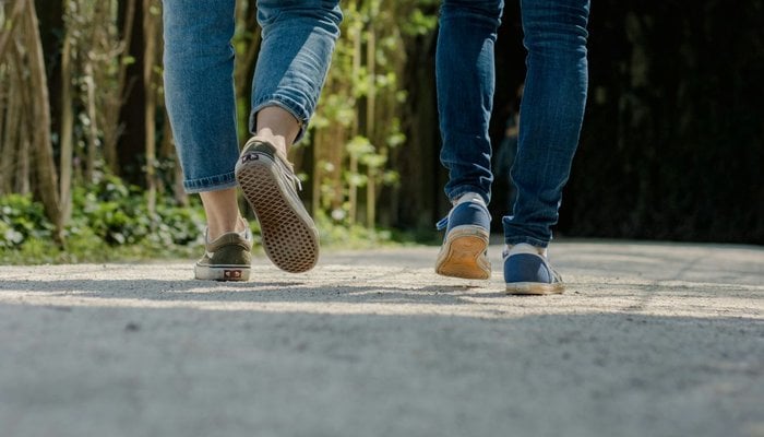 Two people on a walk outside. The image shows their trainers.