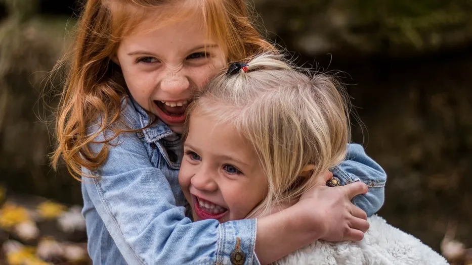 Two young girls hugging each other and smiling