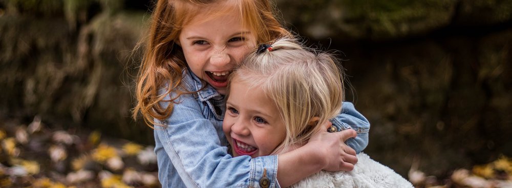 Two young girls hugging each other and smiling