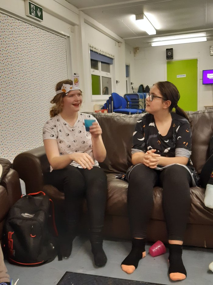 Two young happy girls sitting on  a couch playing a game