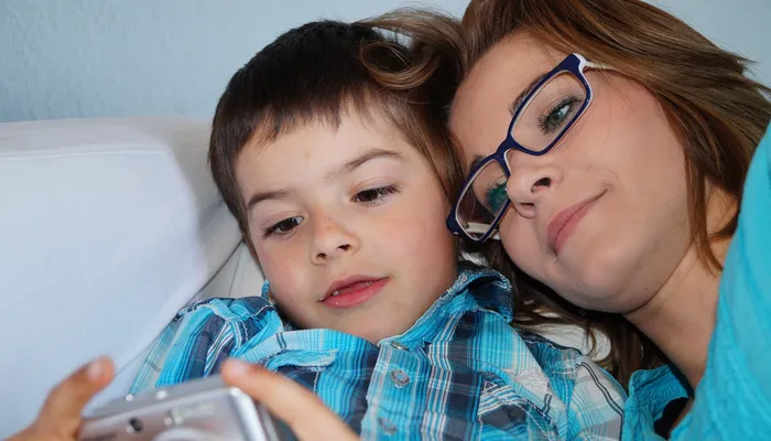 Mother and son laying on the sofa looking at photos on camera screen
