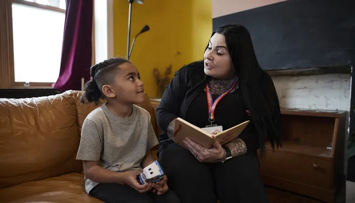 Support worker reads with child on sofa