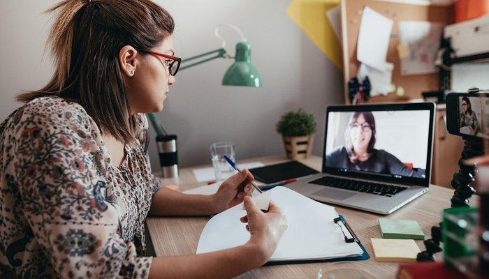 Woman sat at desk talking to another woman on a video call