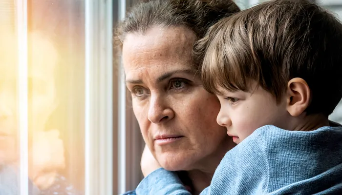 Worried looking mum holding son and looking out the window