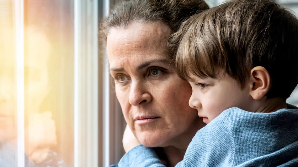 Worried looking mum holding son and looking out the window