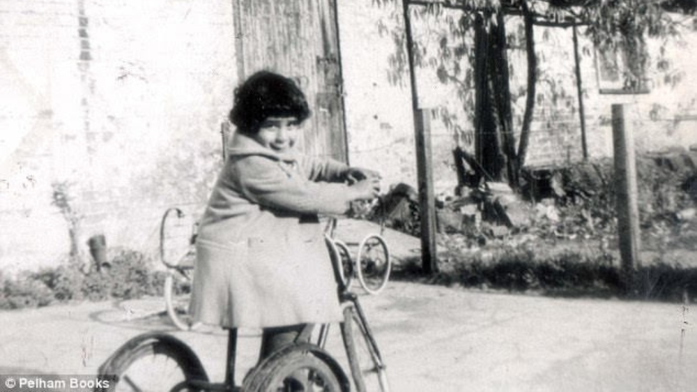 Young Fatima Whitbread smiles while riding on a bike