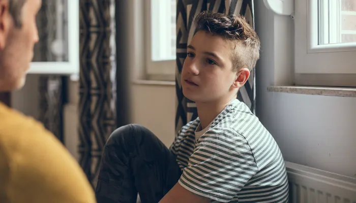 Young boy seated looking at his father with a straight face