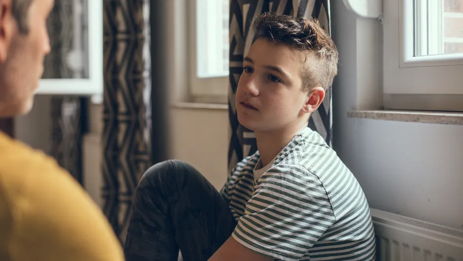 Young boy seated looking at his father with a straight face