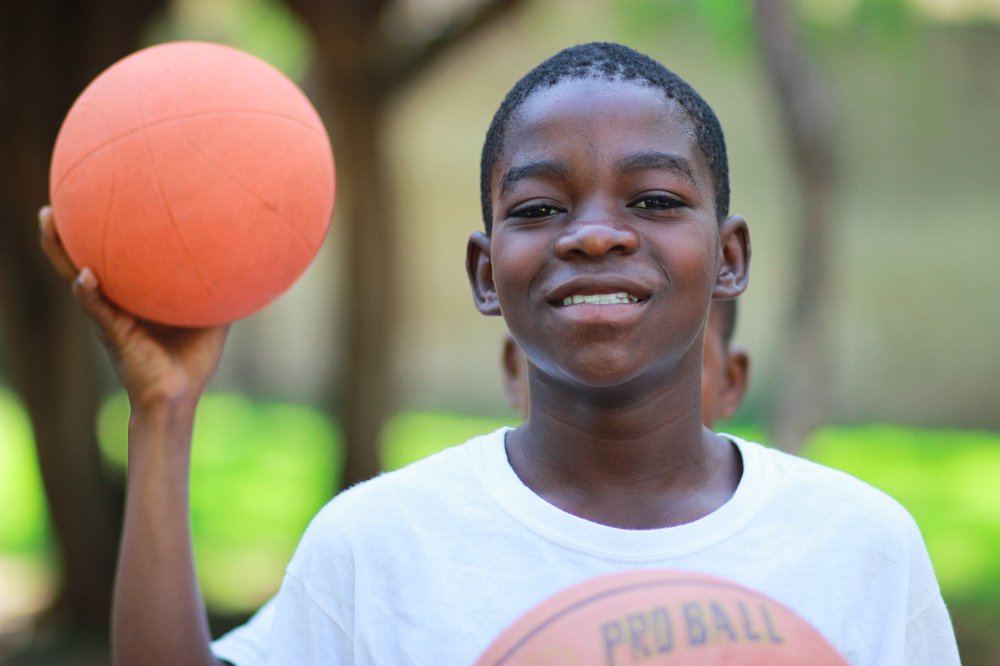 Young boy smiling and holding basketball in park