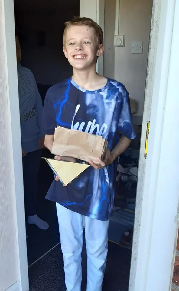 Young boy standing at his door holding a parcel with deliveries from Action for Children Staff.jpg