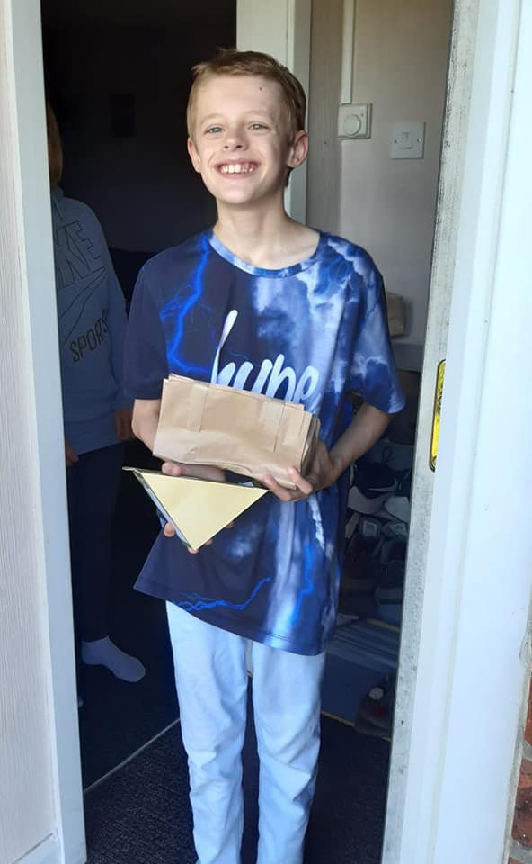 Young boy standing at his door holding a parcel with deliveries from Action for Children Staff.jpg