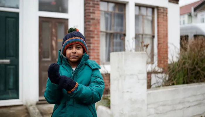Young boy wearing coat and gloves outside
