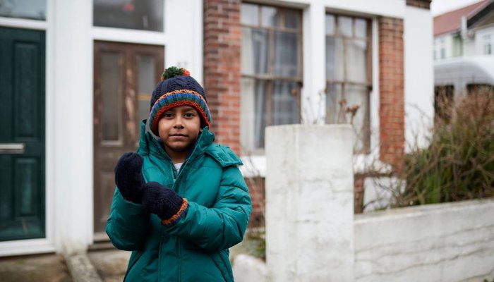 Young boy wearing coat and gloves outside