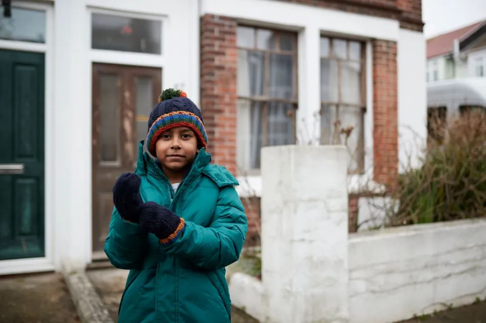Young boy wearing coat and gloves outside