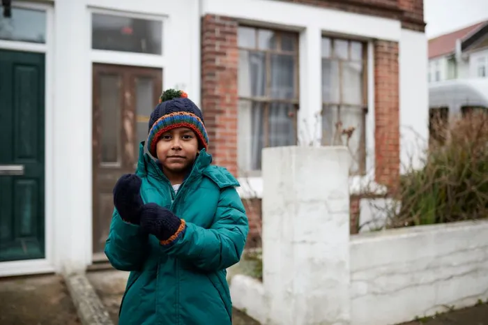 Young boy wearing coat and gloves outside