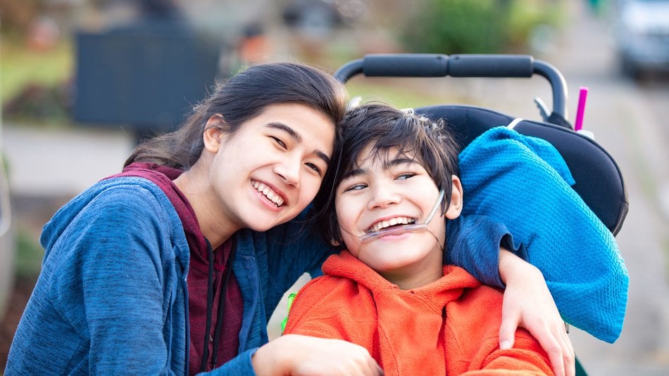 Happy young boy in a wheelchair posing with his sister