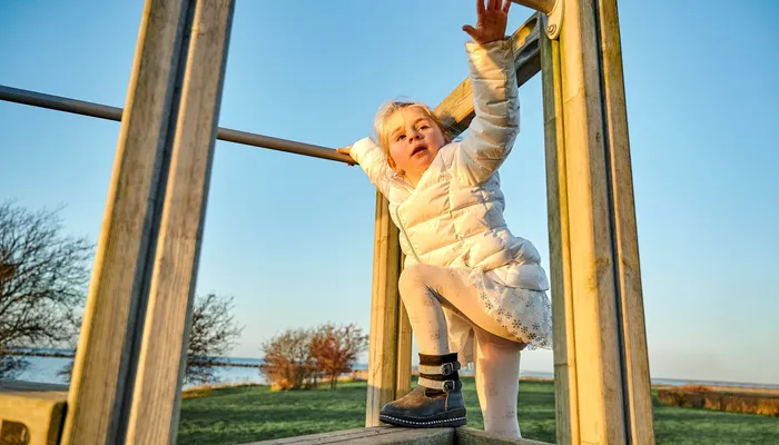 Young girl climbing outdoors on a jungle gym at a park.jpg