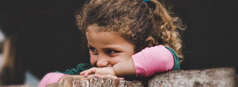 Young girl resting on tree trunk and smiling