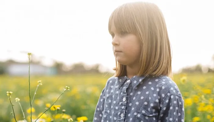 Young girl standing in field of flowers looking worries.jpg