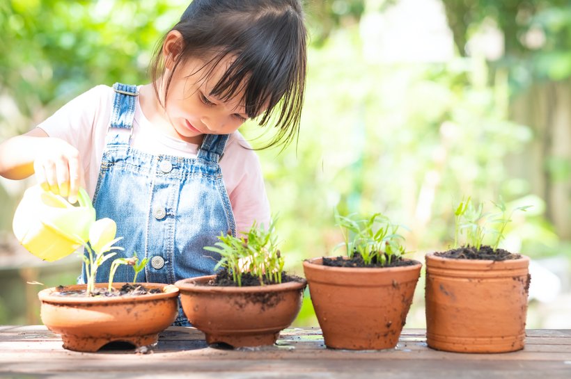 Young girl watering her sprouting plants outside